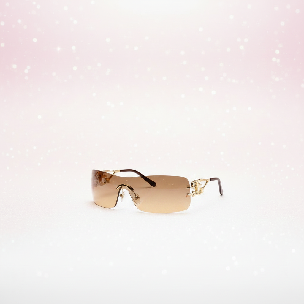 Rimless wraparound shield sunglasses at a 3/4 angle on a light pink gradient sparkle background