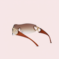 Rimless wraparound shield sunglasses with brown gradient lenses and gold double heart embellishment